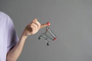 a human hand holding an empty shopping cart as the symbol of online shopping and e-commerce
