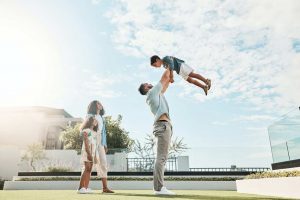 Family, sky and real estate with a man lifting his son outdoor while bonding as a new homeowner gro